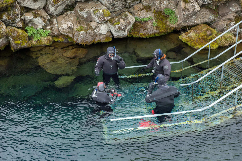 Divers descending into the water for diving in Silfra fissure at Thingvellir National Park in Iceland.