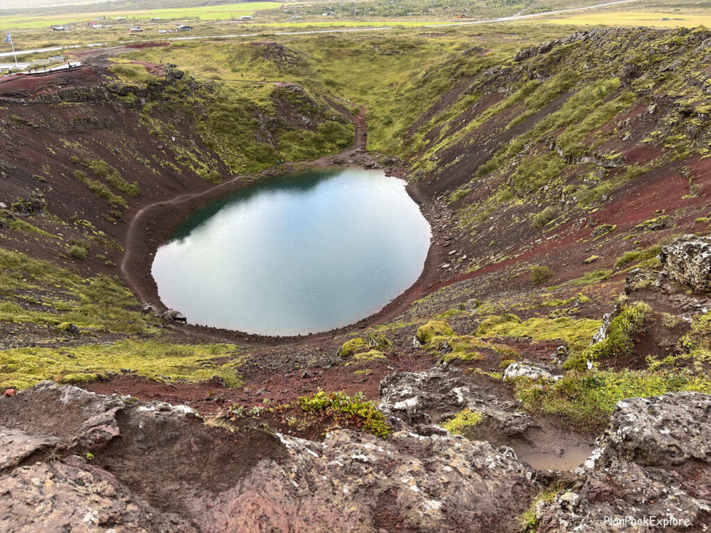 Kerid Crater in Iceland - red rocks with green moss and a blue volcanic lake at the bottom.