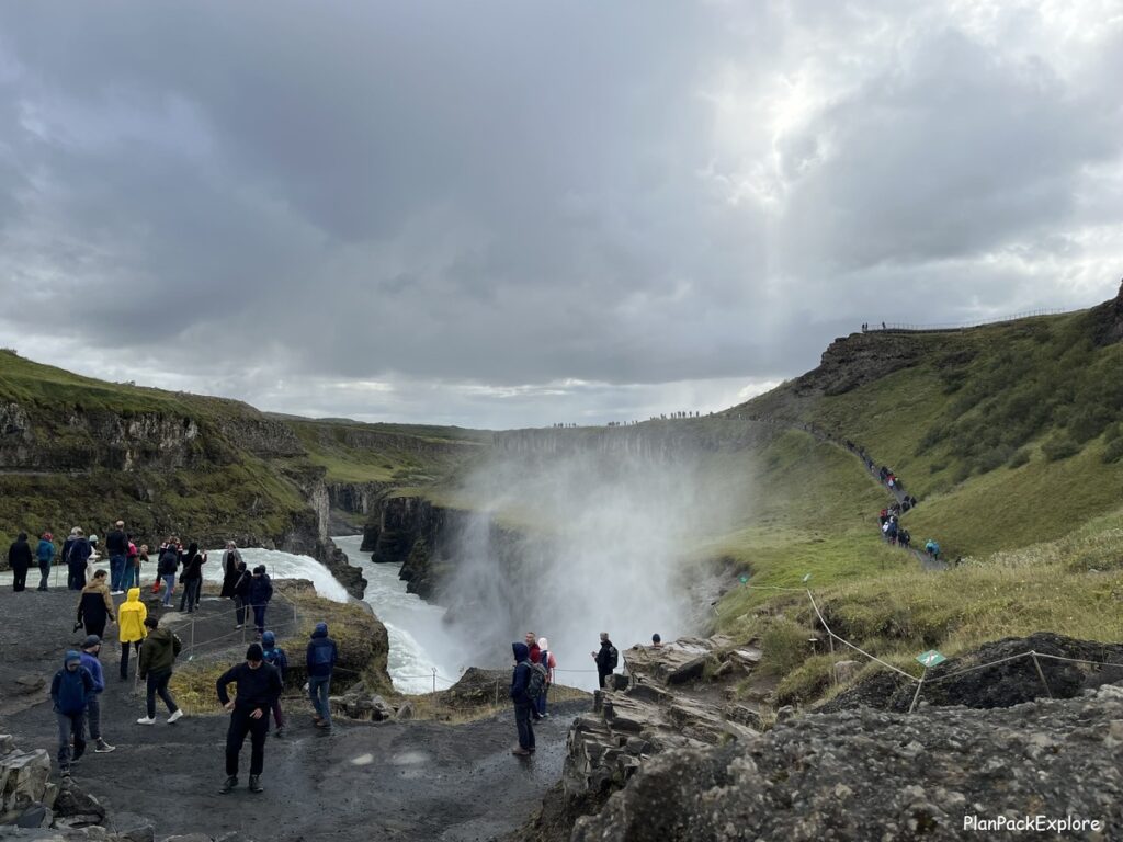 Tourists in an area next to the top of the waterfall, at the end of the path.