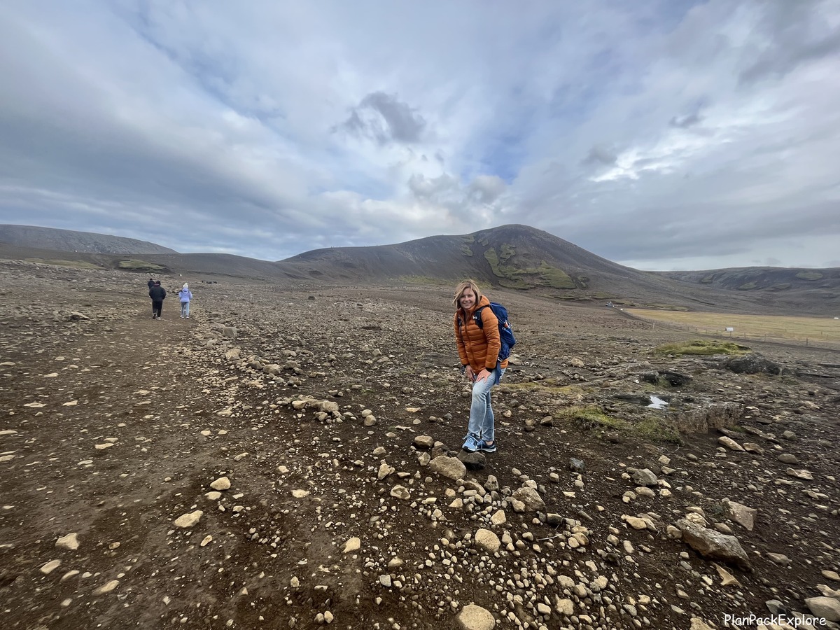 Article author at the trailhead to the viewpoint for Fagradasfjall volcano, which is in the background of the picture. The trail is a brown gravel path.