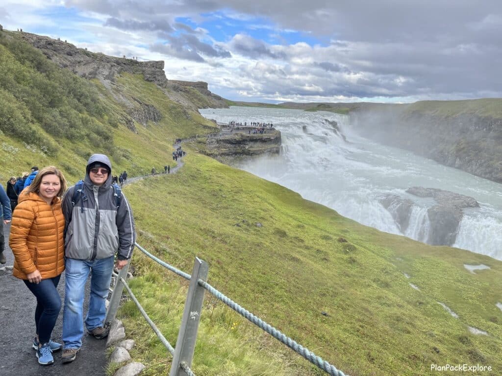 A couple standing on the path next to Gullfoss waterfall in Iceland.