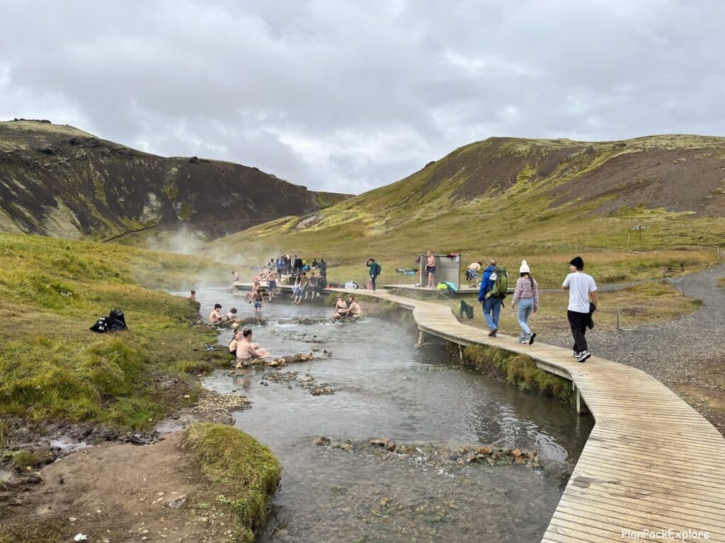 People walking on the wooden platforms of Reykjadalur Valley, near the hot river.