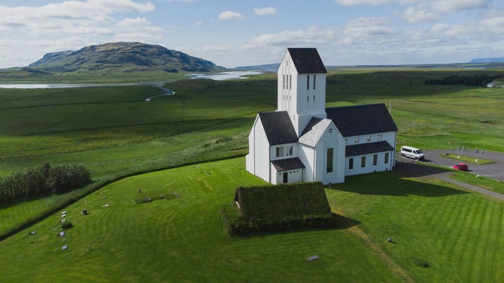 Skalholt Cathedral in Iceland (white church with a dark roof) and a turf house next to it.