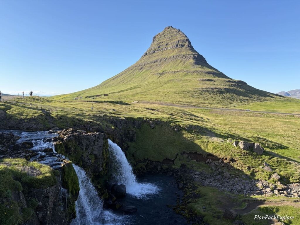 A pointy green mountain called Kirkjufell Mountain and the waterfall on Snaefellsnes Peninsula in Iceland.