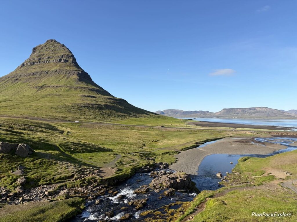 A pointy green mountain called Kirkjufell Mountain and a river next to it on Snaefellsnes Peninsula in Iceland.