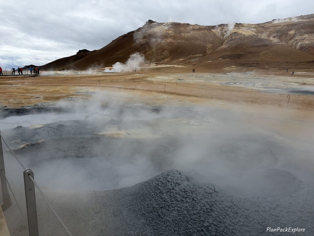 Steaming vents and mud pools in golden colored soil at Hverir Geothermal Area in Iceland.