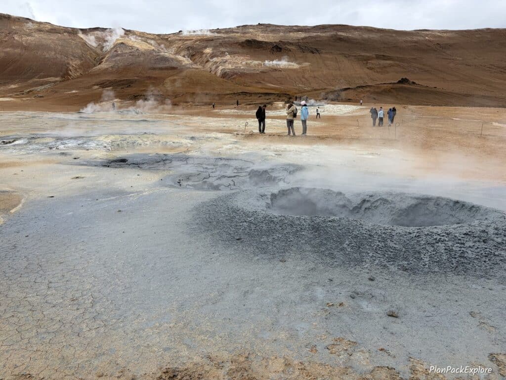 Steaming vents and mud pools in golden colored soil at Hverir Geothermal Area in Iceland.