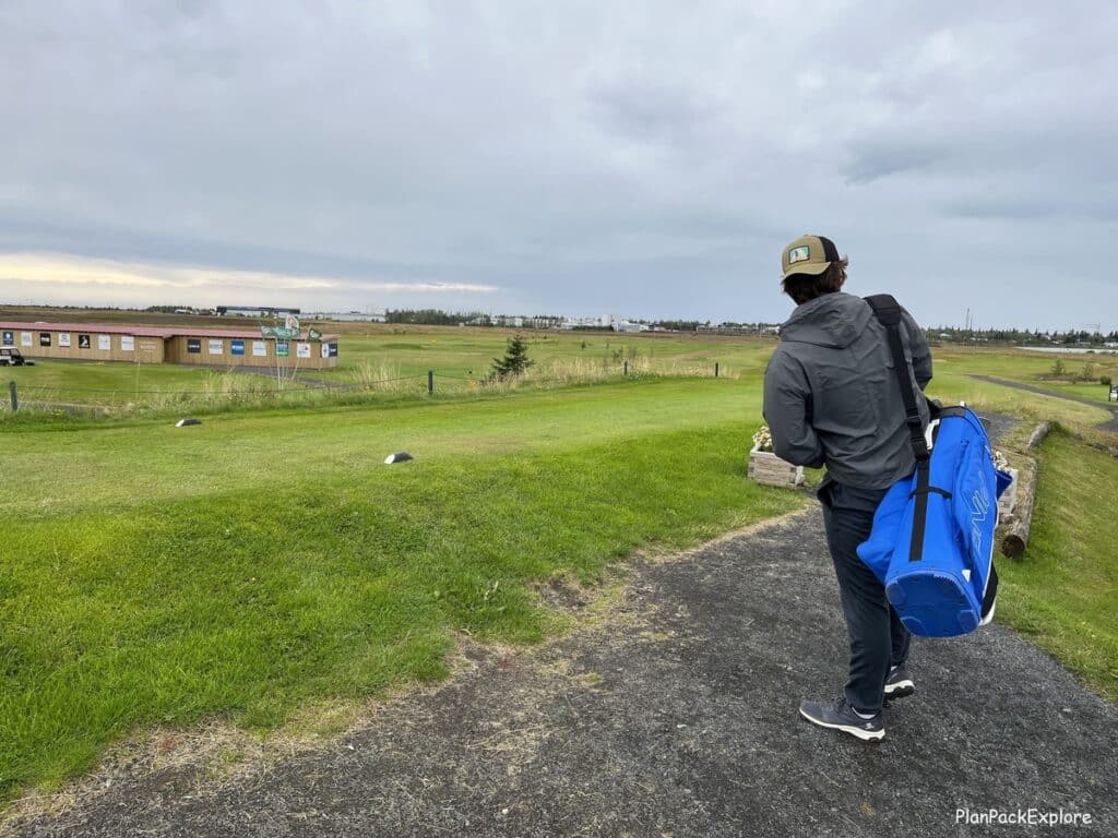 A man with a golf bag at a golf course in Iceland.