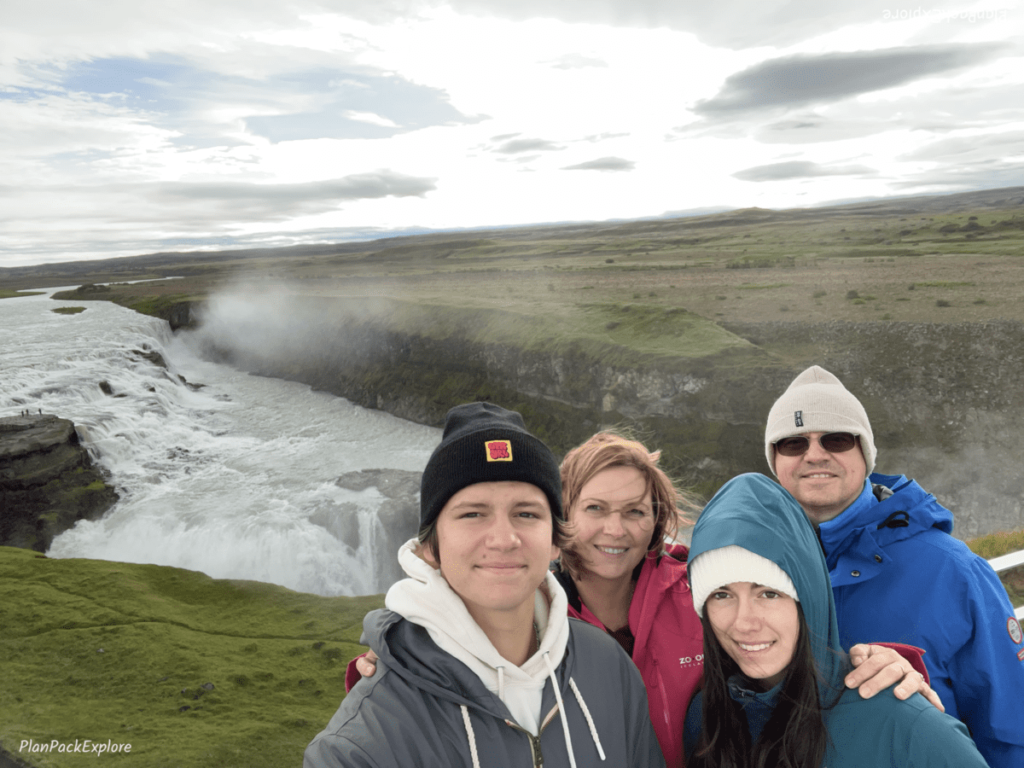 A selfie of a 4 people family in front of the Gullfoss waterfall in Iceland.