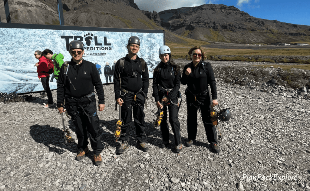 Troll Expeditions parking lot, a family of four in helmets, and harnesses ready for ice climbing on Vatnajokull Glacier.
