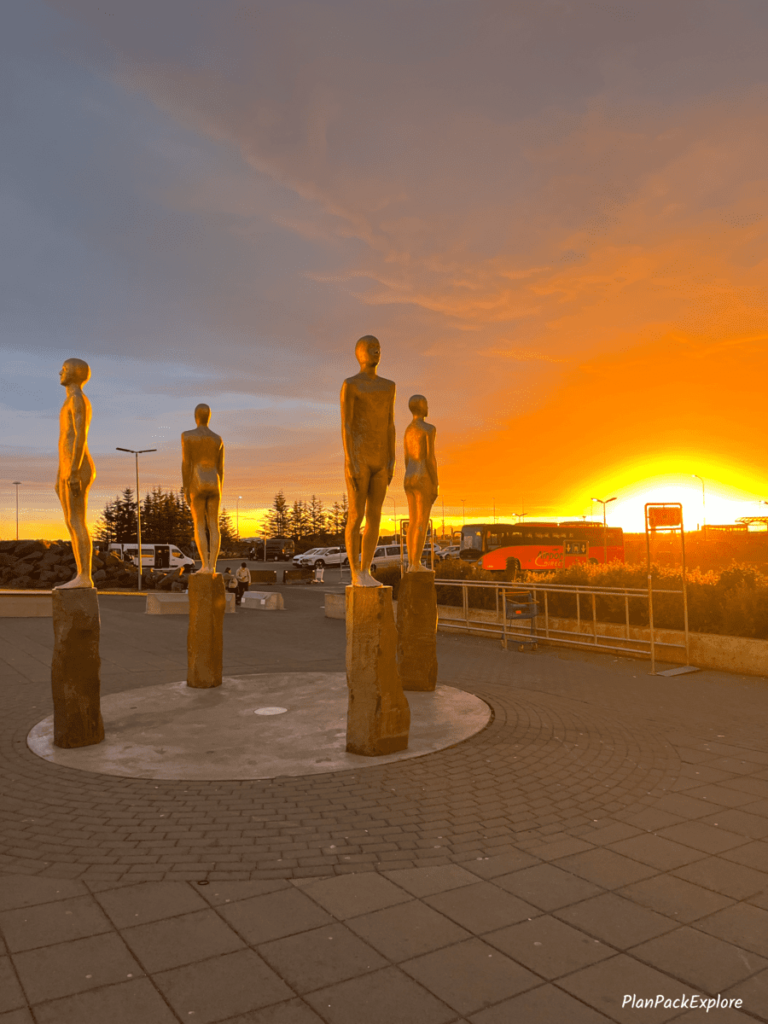 Sunrise at Keflavik airport in Iceland. A statue of 4 people in orange light.