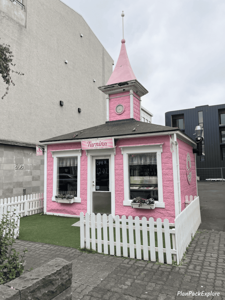 Akureyri, Iceland - a light pink building with a small white fence.
