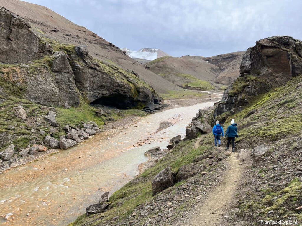 People on the narrow trail by the river leading to Kerlingarfjoll hot spring in Iceland. Glacier visible in the distance.