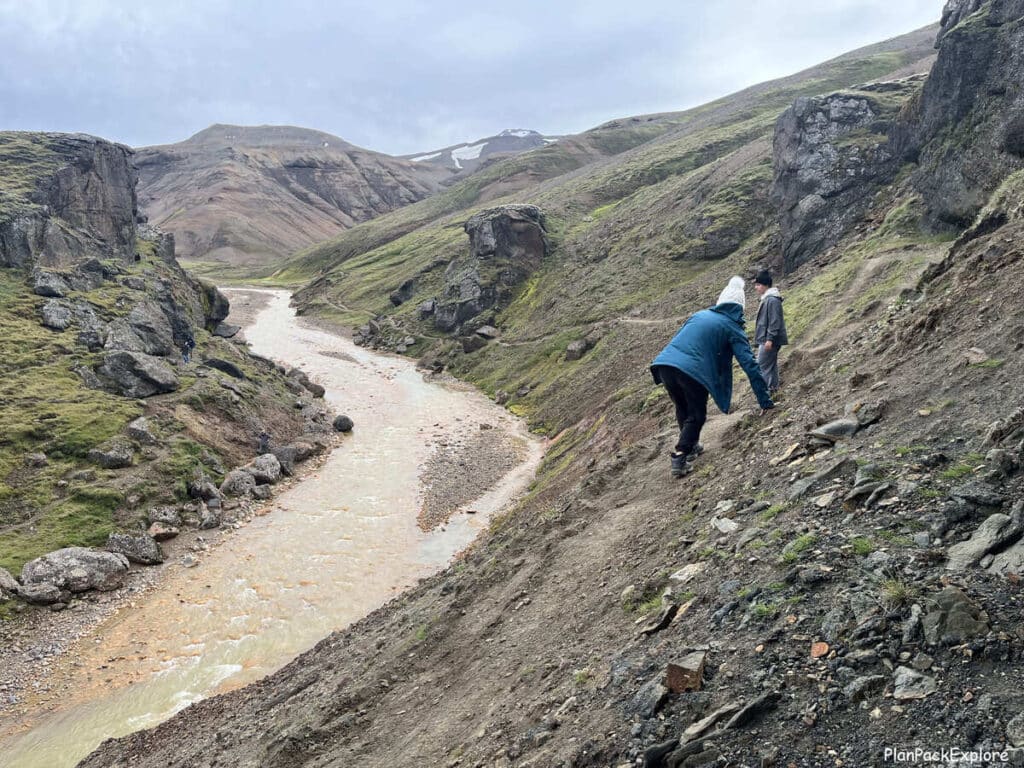 People holding on to the side of the narrow trail by the river leading to Kerlingarfjoll hot spring in Iceland.