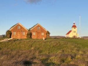 Two turf houses and a small white church with a red roof at Modrudalur Farm in Iceland.
