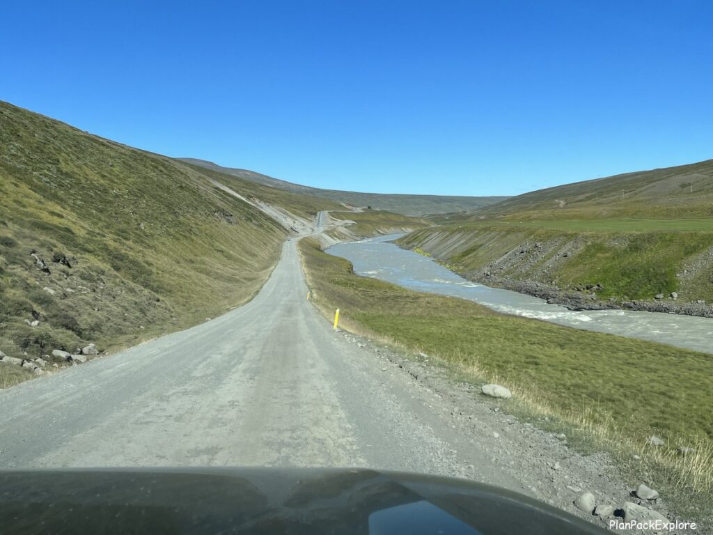 A narrow gravel road with a river next to it, leading to Studlagil Canyon in Iceland.