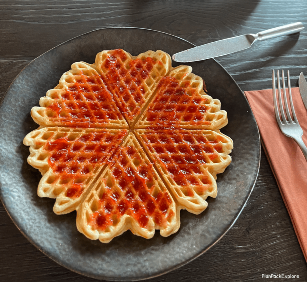 A dark plate with heart shapes waffles with jam.