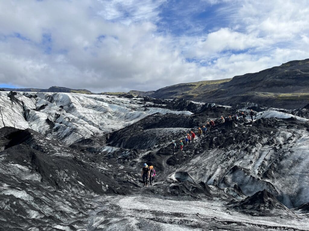 People hiking on the ash-covered Solheimajokujj glacier in Iceland.