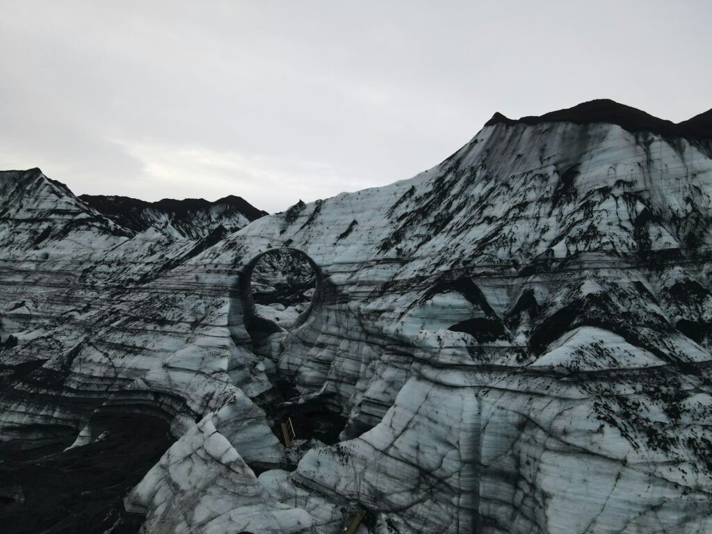 Katla ice cave tunnel in Iceland - glacier streaked with black ash visible.