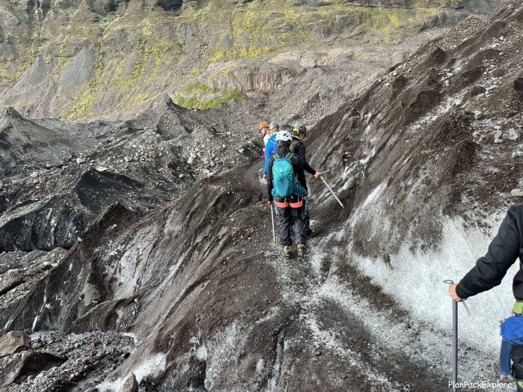 People hiking on a narrow trail on the side of Vatnajokull glacier in Iceland.