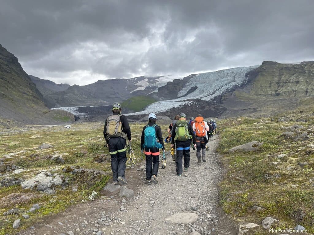 People on the gravel path dressed in helmets and harnesses going for an ice climbing tour on Vatnajokull glacier in Iceland.