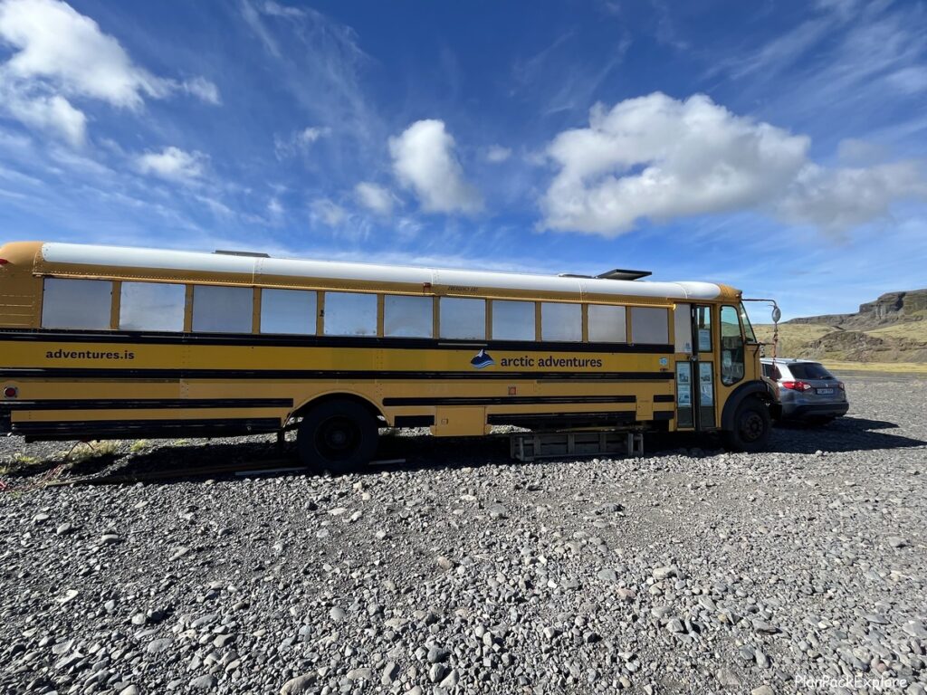 A big yellow school bus in a parking lot of Solheimajokull glacier in Iceland.