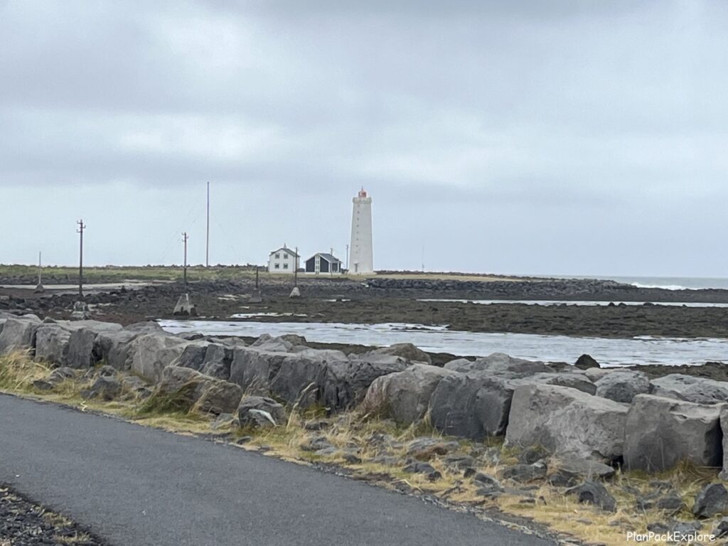 A white lighthouse at the end of a paved path in Reykjavik Iceland.