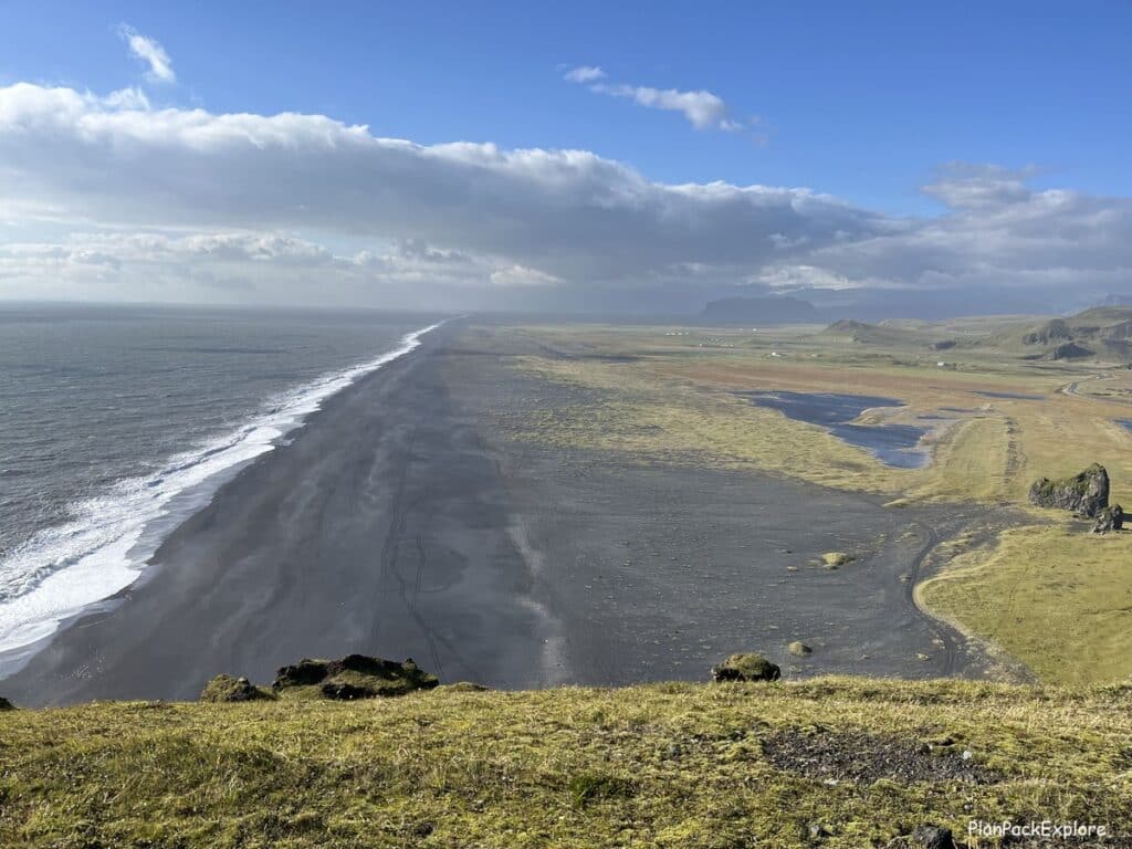 A vast black sand beach near Dyrholaey cliffs in Iceland.