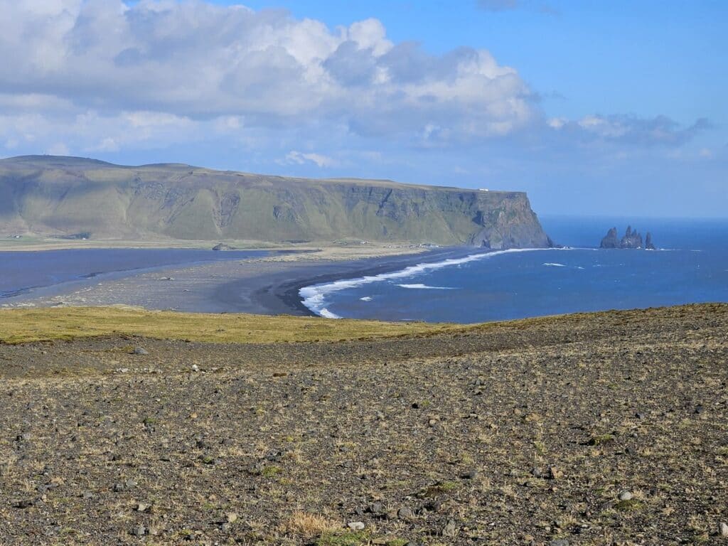 Black sand beach near the ocean and tall cliffs in South Iceland.