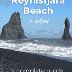 A view of Reynisfjara black sand beach in Iceland, featuring ocean waves and rock formations in the background.