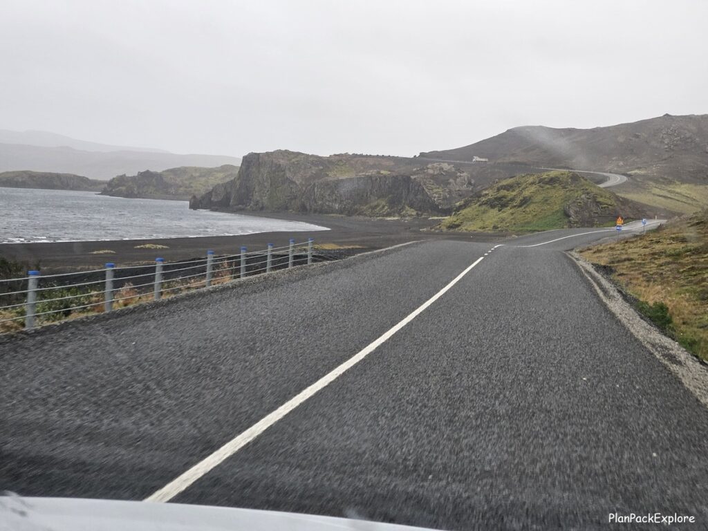 A paved road next to a lake in volcanic mountains of reykjanes peninsula in Iceland.