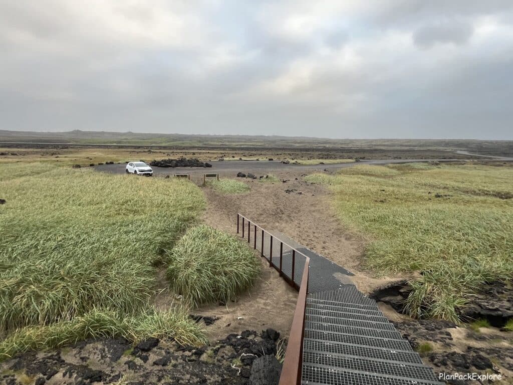 Metal stairs and a view of the parking lot for Brimketill Lava rock Pool on Reykjanes Peninsula in Iceland.