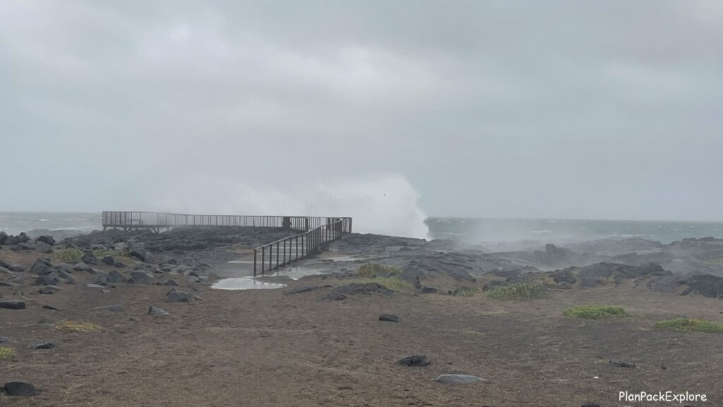 A viewing platform with huge waves behind it at Brimketill Lava rock Pool on Reykjanes Peninsula in Iceland.