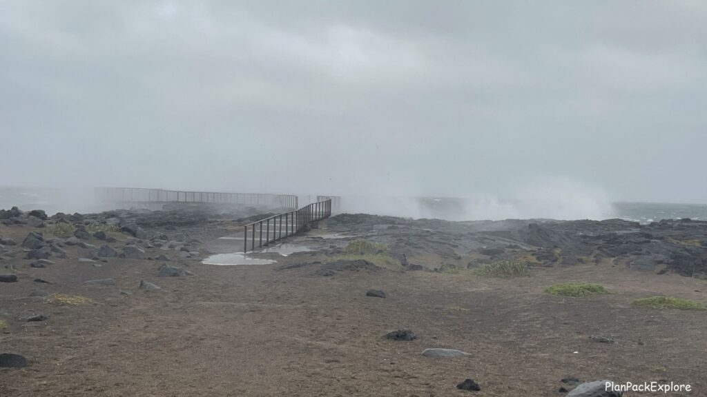 A viewing platform with huge waves behind it at Brimketill Lava rock Pool on Reykjanes Peninsula in Iceland.
