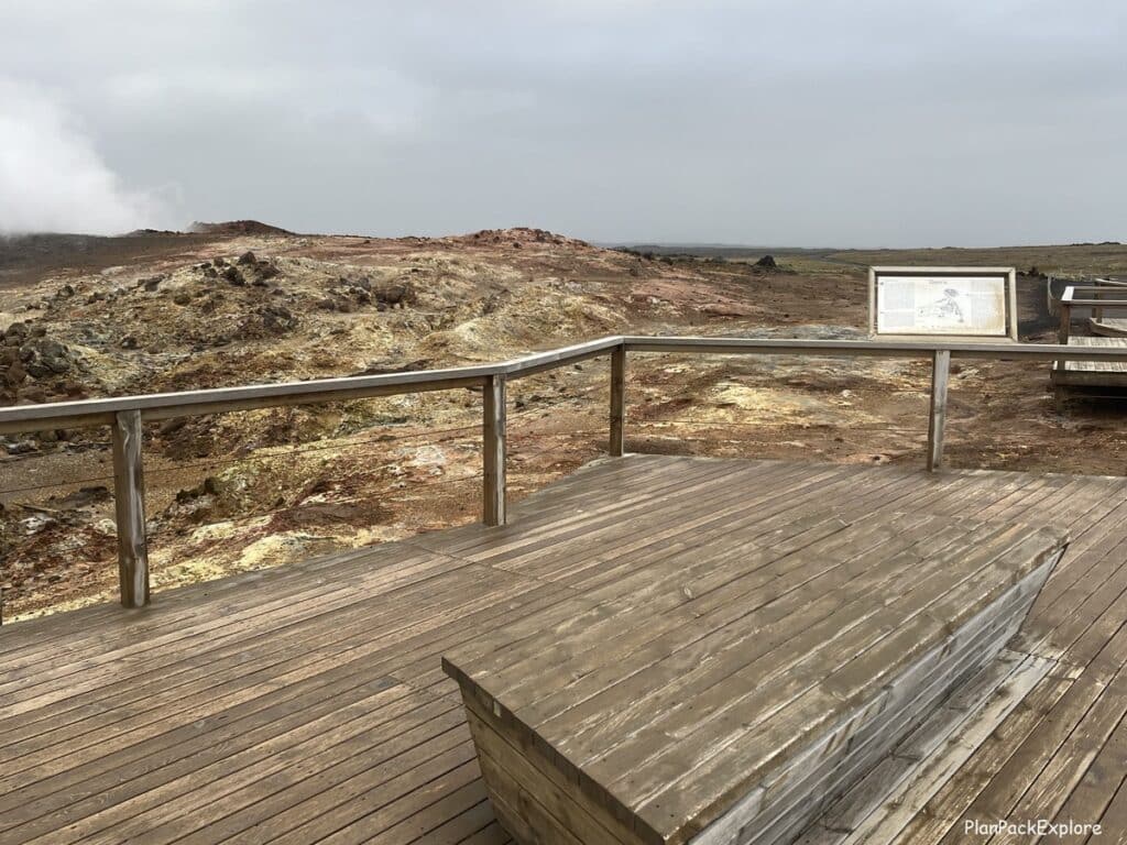 A wooden boardwalk with an info sign at Gunnuhver Geothermal area on Reykjanes peninsula in Iceland.