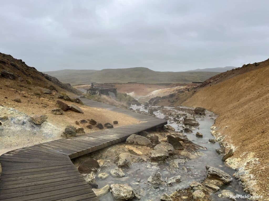 A steaming stream and a wooden boardwalk in Seltun geothermal area on reykjanes peninsula in Iceland.