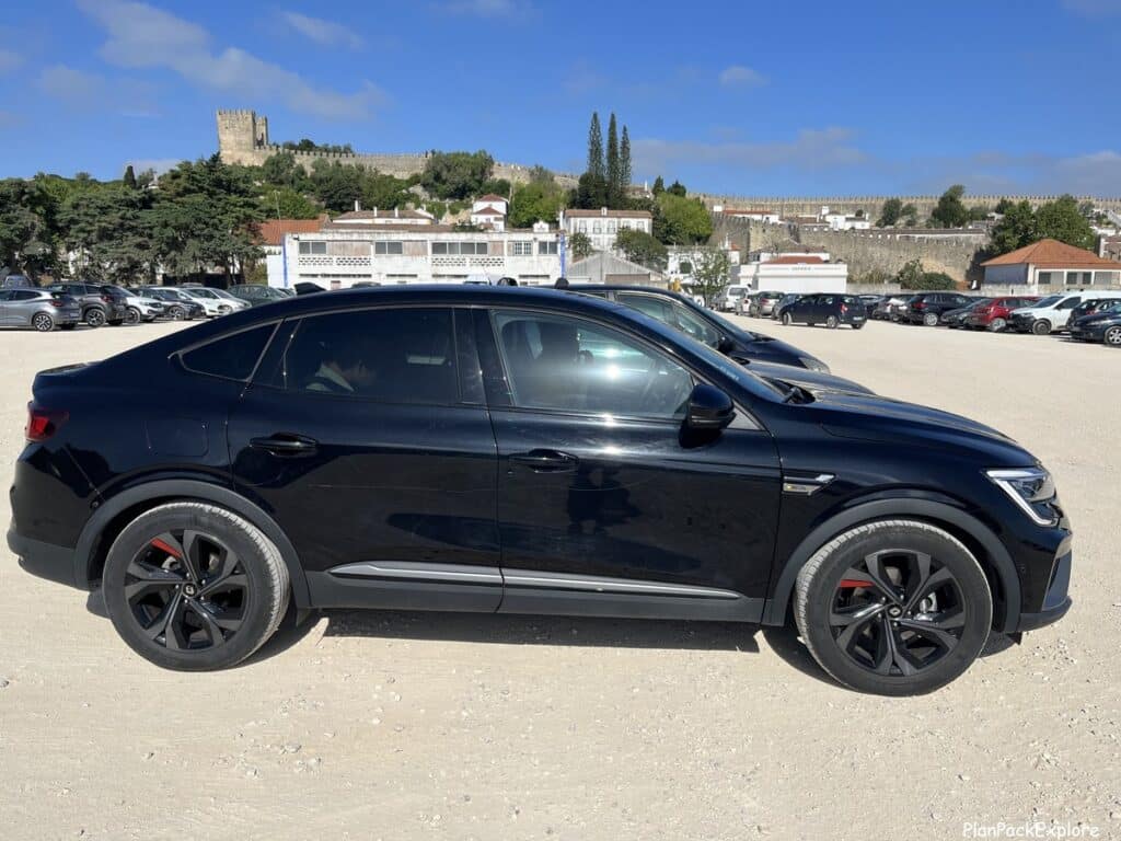 A black car in a gravel parking lot in Obidos, Portugal.
