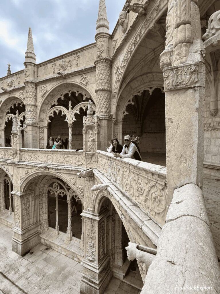Two people at the carved balcony of the cloister in Jeronimos Monastery in Lisbon.