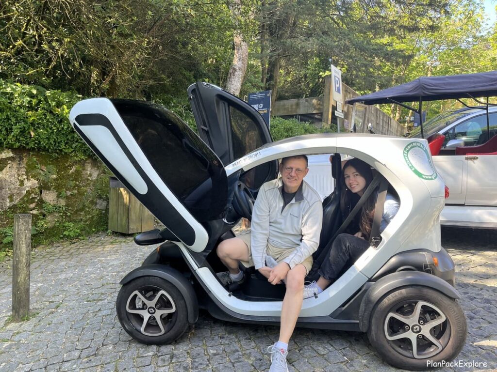 Two people sitting inside a black and white e-car, called Twizy in Sintra, Portugal.