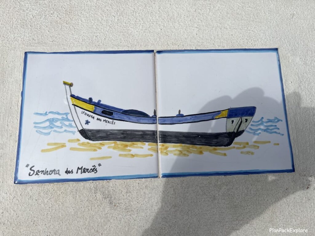 A picture of a fishing boat made of tiles on a white concrete post in Carvoeiro Boardwalk in the Algarve, Portugal.
