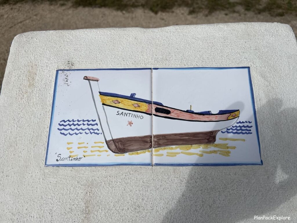 A picture of a fishing boat made of tiles on a white concrete post in Carvoeiro Boardwalk in the Algarve, Portugal.