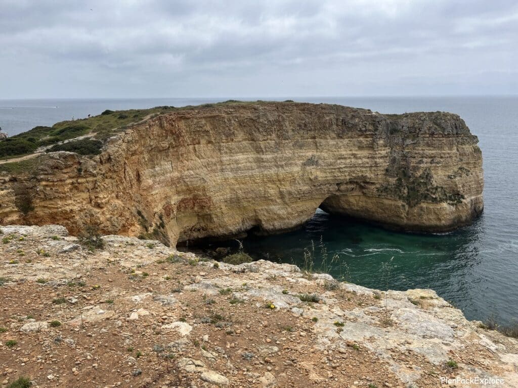 Tall cliffs with an arch in the ocean along the trail of the headlands in Portugal.