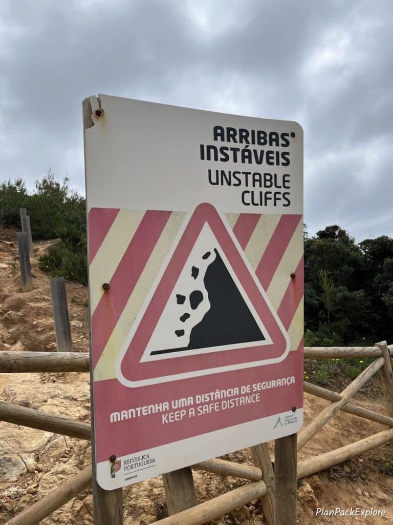 A sign warning hikers about unstable cliffs on the trail of the headlands in Portugal.
