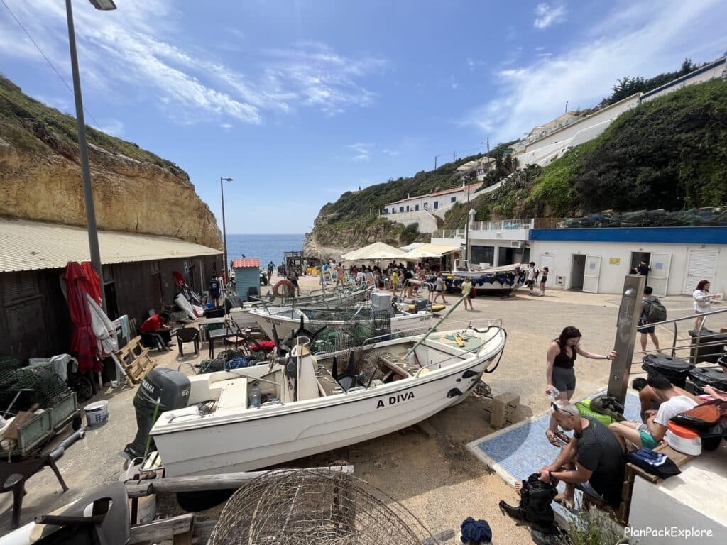 Small boats and a few tourists in the parking lot of Benagil Beach in the Algarve, Portugal.