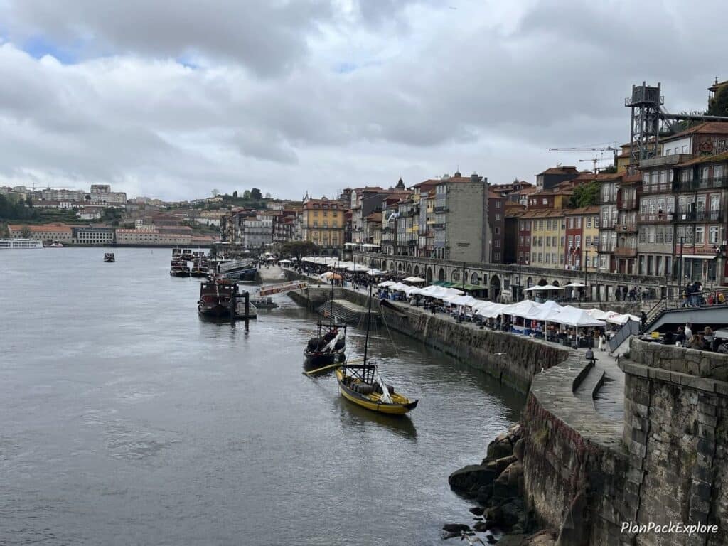 A riverside promenade with colorful houses and souvenir stalls in porto.