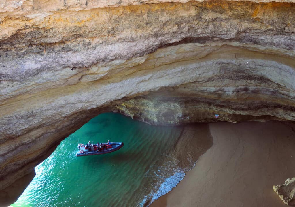 A small pontoon boat entering a sea cave called Benagil Cave in Portugal.