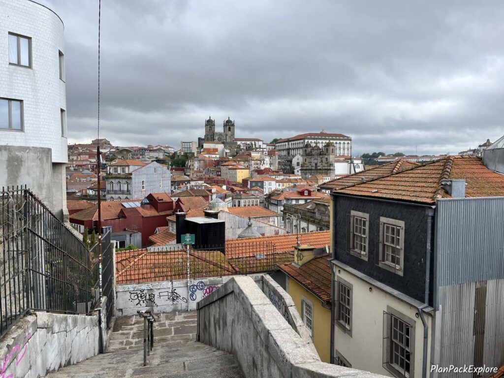 Stone stairs leading to the Ribeira district of Porto with red rooftops in the backgroud.