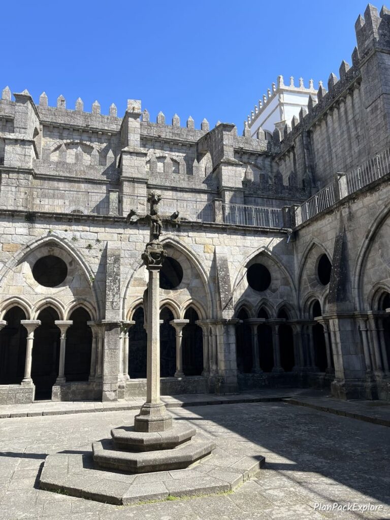 A stone courtyard with a cross in the middle at the Porto Cathedral.