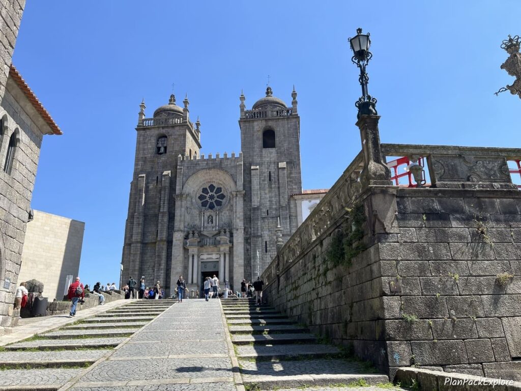 A large stone building and a walkway of the Porto Cathedral in Porto, Portugal.