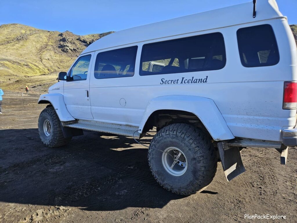 A large white super jeep parked in the gravel parking lot at Laki in Iceland.